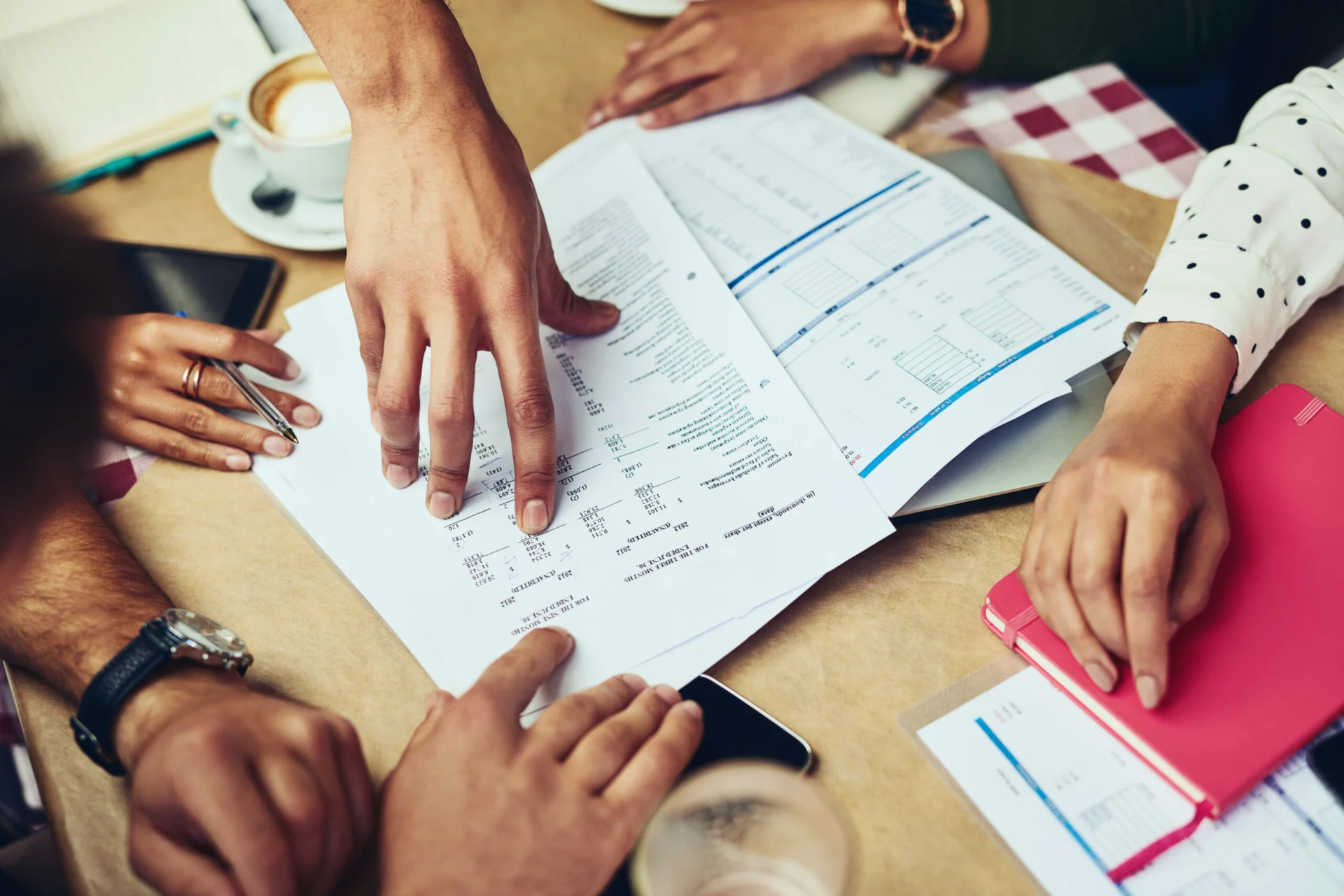 Paperwork, hands and meeting for budget, desk and planning for project, event coordinator and group. Office, teamwork and documents for proposal, funding and report of costs, communication and people.